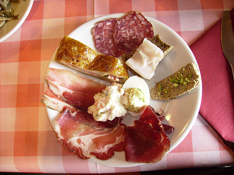 Antipasti misti: affettati, torta salata, lardo con pane nero, patè di capriolo, uovo a sorpresa